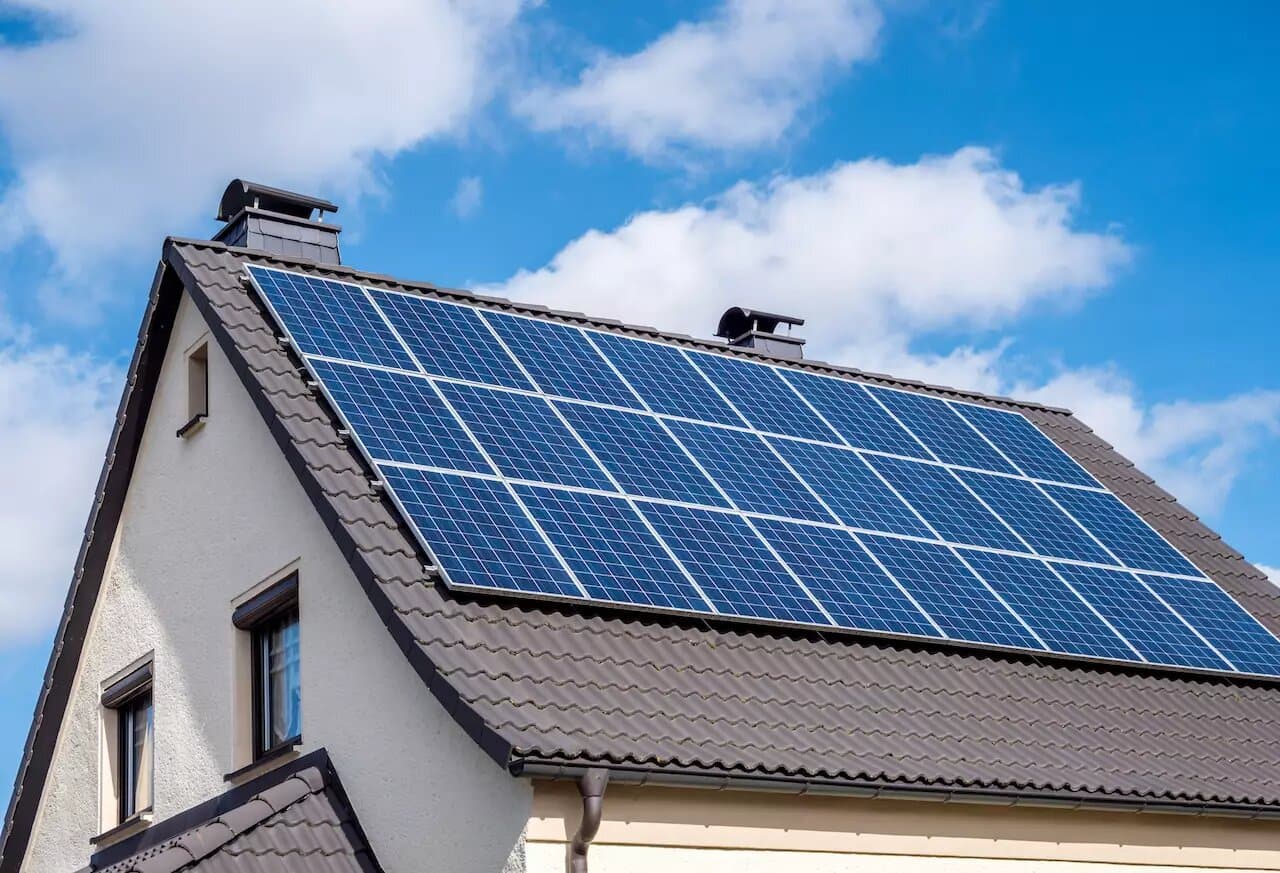 Maison avec panneaux photovoltaïques sous ciel bleu